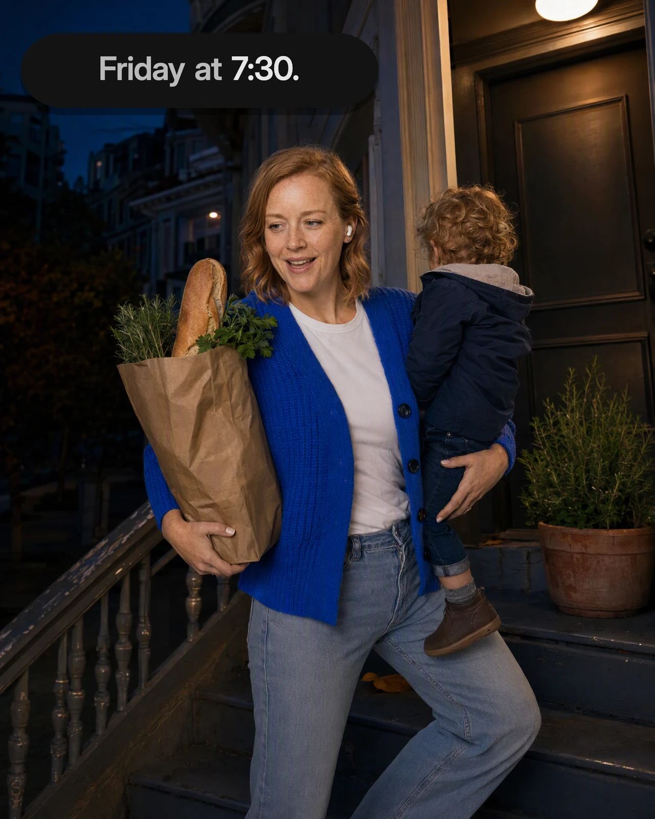 A mom climbs her front steps at dusk with her toddler on her hip and a grocery bag, talking to Dvina hands-free; the call floats beside her with its live captions.