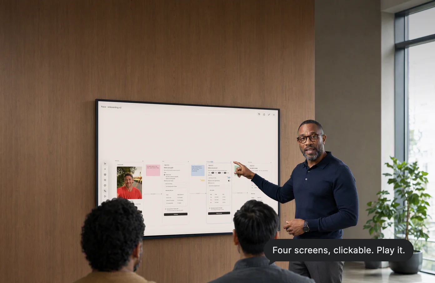 A design lead walks two teammates through an onboarding flow on the wall display; Dvina’s answer: Four screens, clickable. Play it.