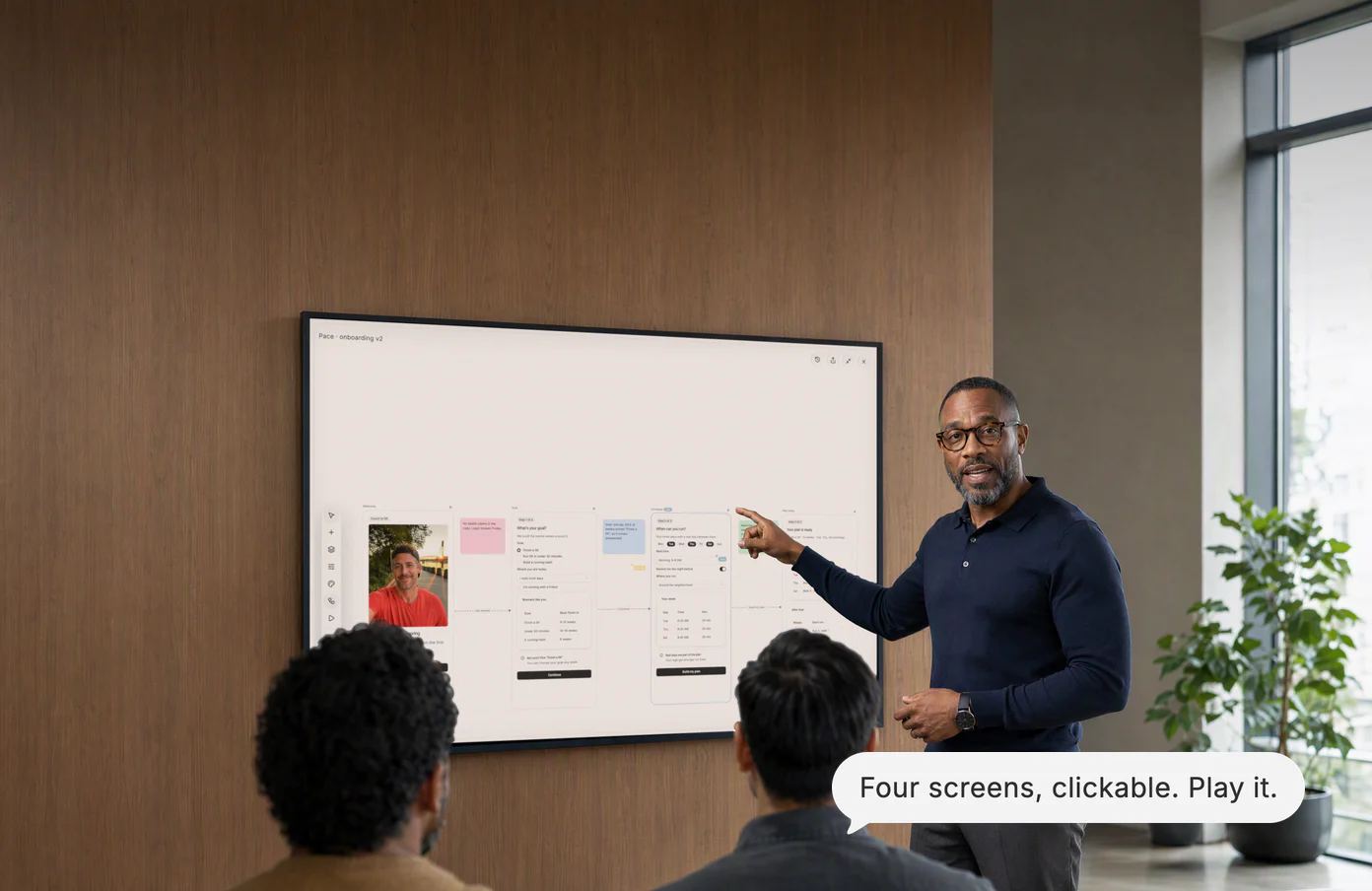 A design lead walks two teammates through an onboarding flow on the wall display; Dvina’s answer: Four screens, clickable. Play it.