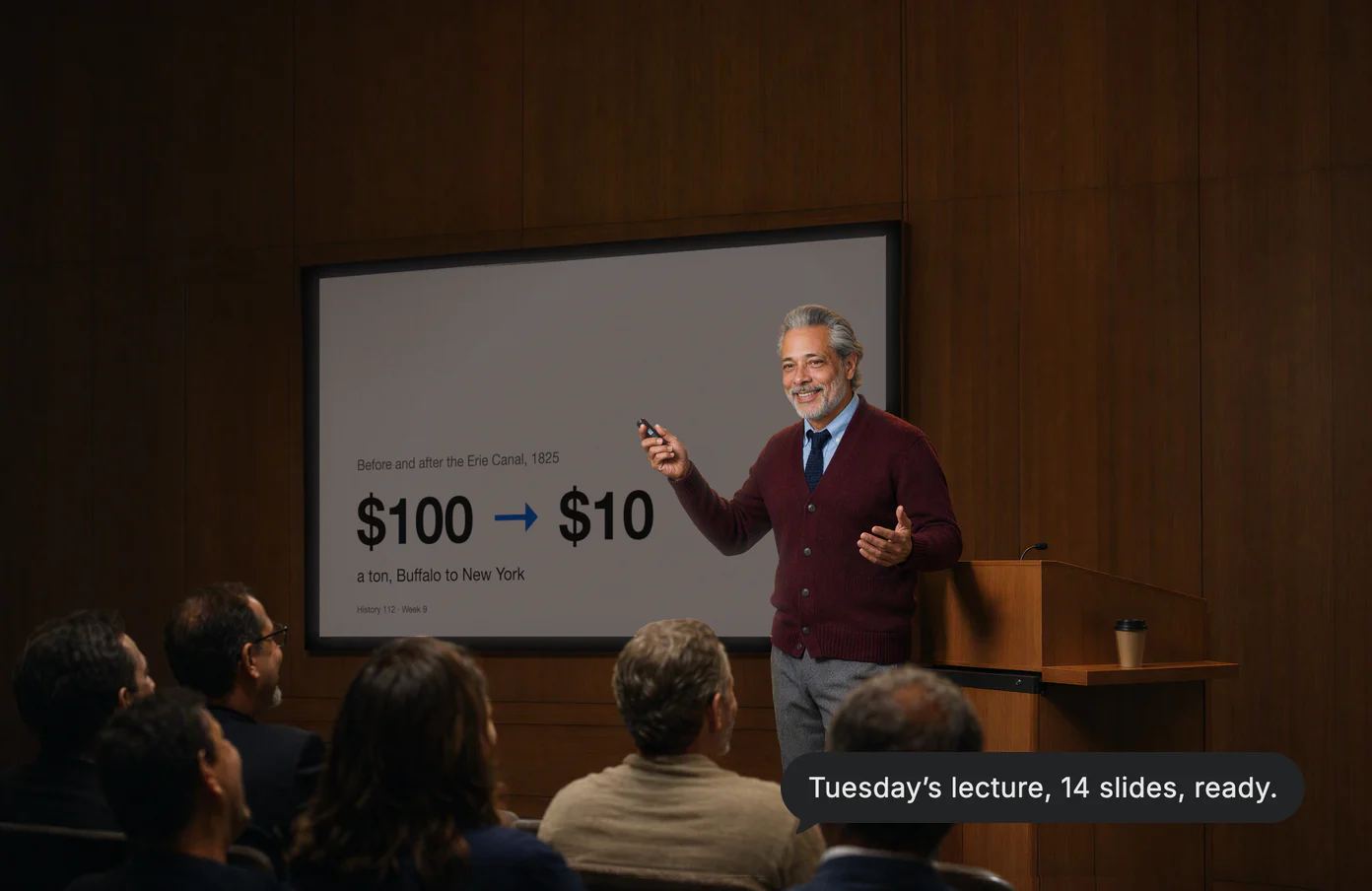 A history teacher clicks to his next slide as the lecture hall laughs; Dvina’s answer: Tuesday’s lecture, 14 slides, ready.