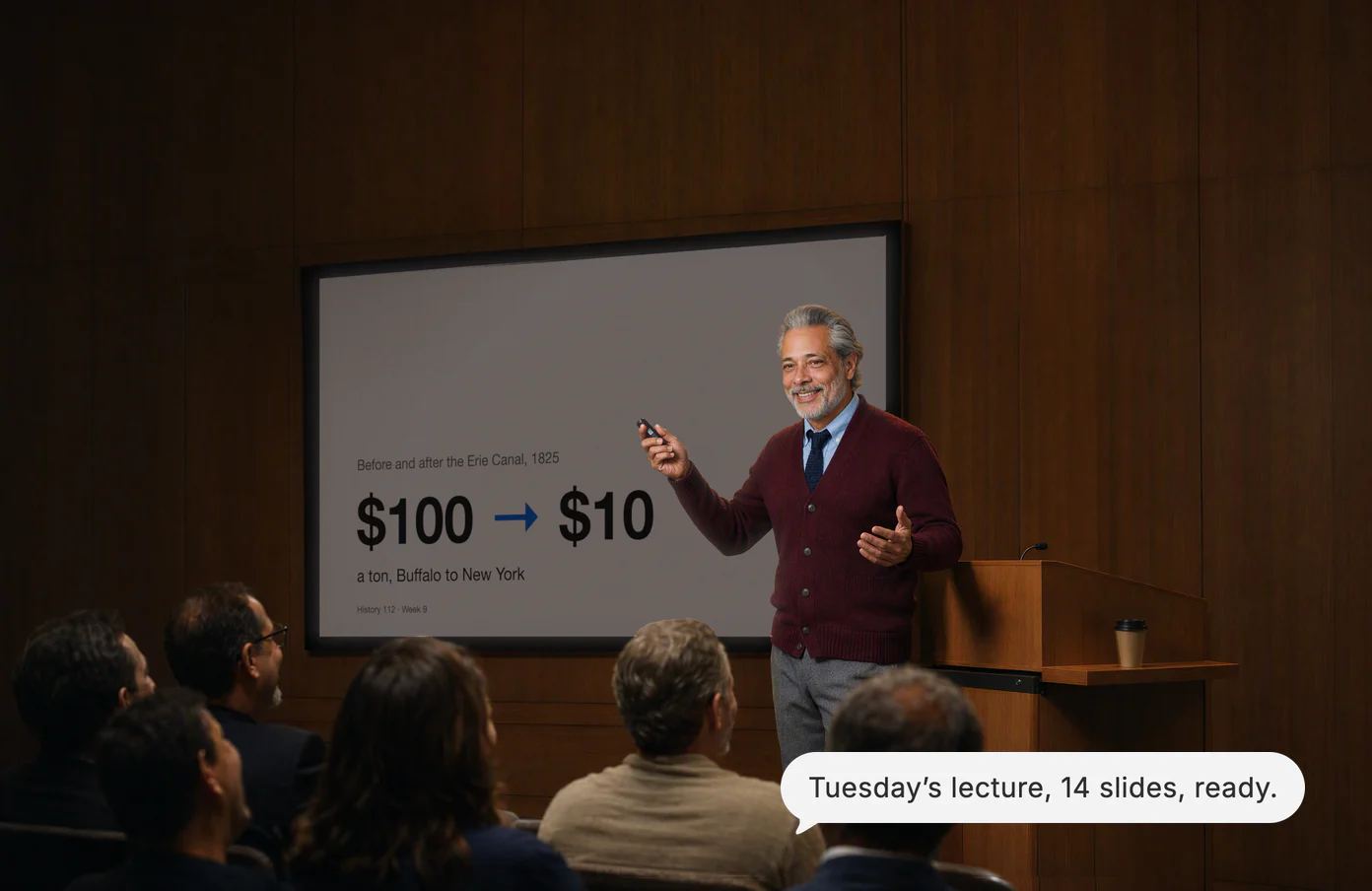 A history teacher clicks to his next slide as the lecture hall laughs; Dvina’s answer: Tuesday’s lecture, 14 slides, ready.