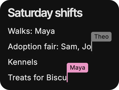 A shared page in Dvina, Saturday shifts, with two people writing on it at once: Theo’s caret after “Adoption fair: Sam, Jo” and Maya’s mid-word on “Treats for Biscu”.