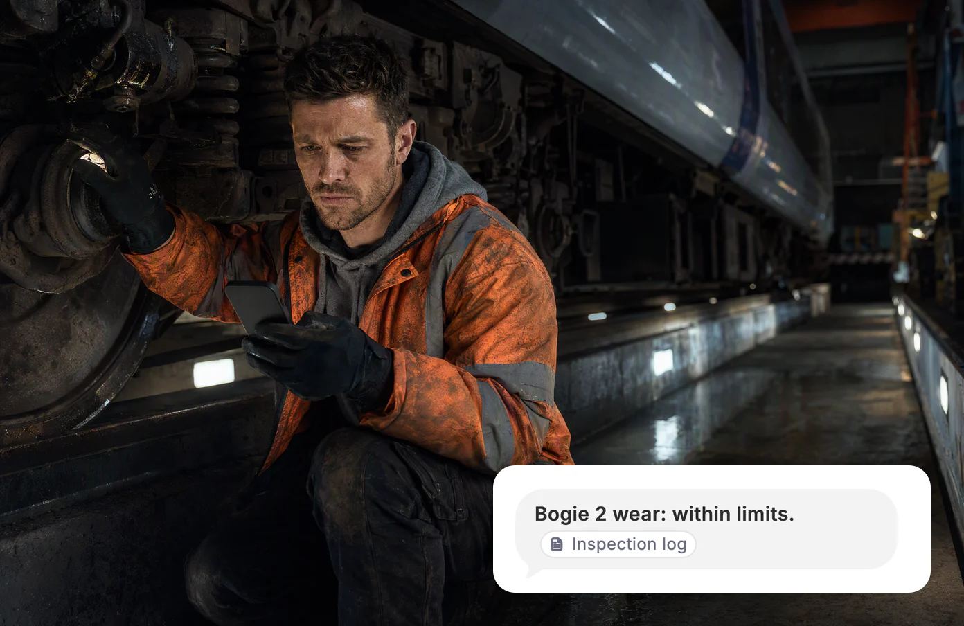 A track engineer crouches by a train’s bogie at a maintenance depot before dawn. Dvina: bogie 2 wear within limits, from the inspection log.