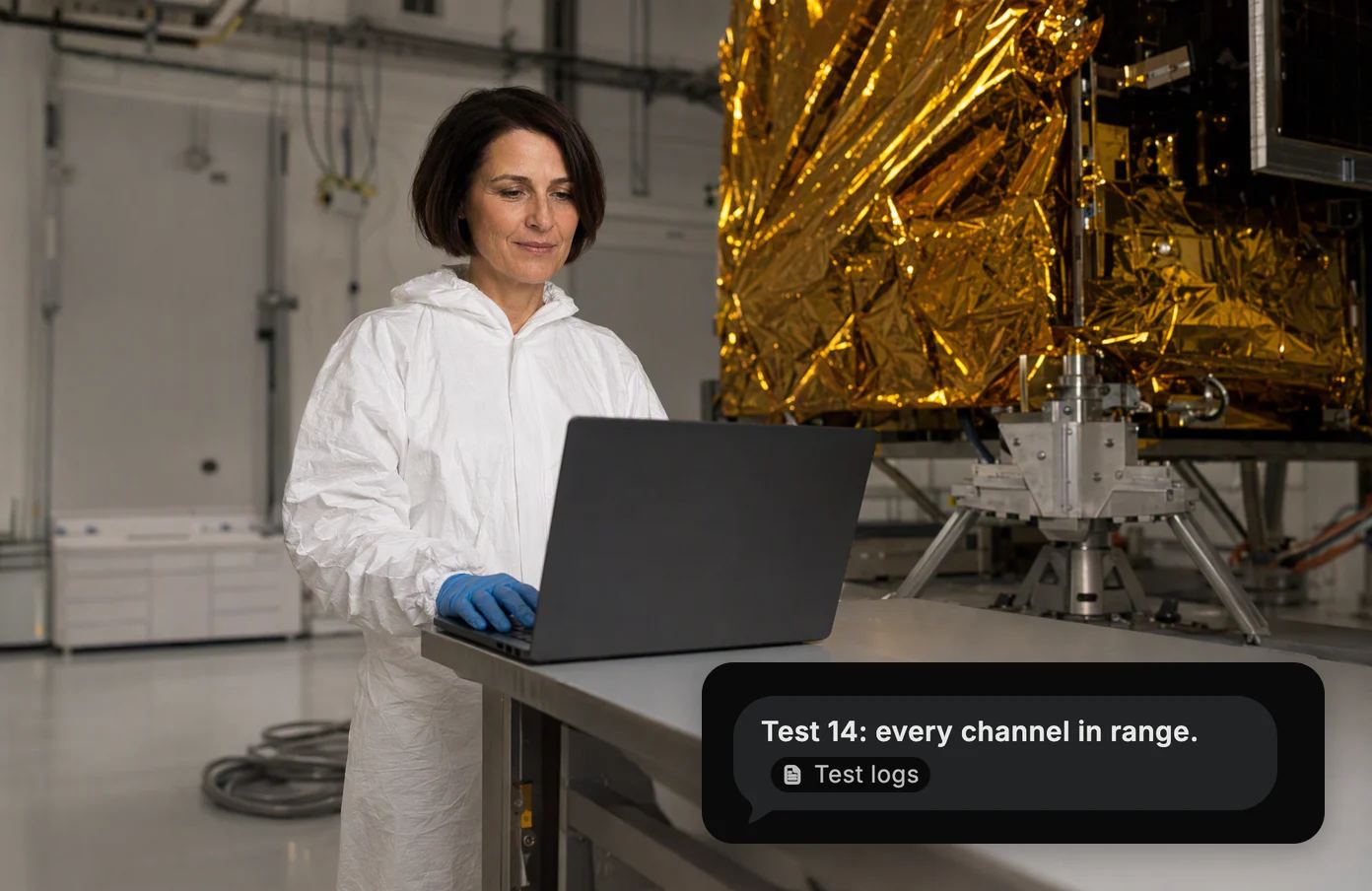 A test engineer at a bench beside a satellite wrapped in gold foil. Dvina: test 14, every channel in range, from the test logs.