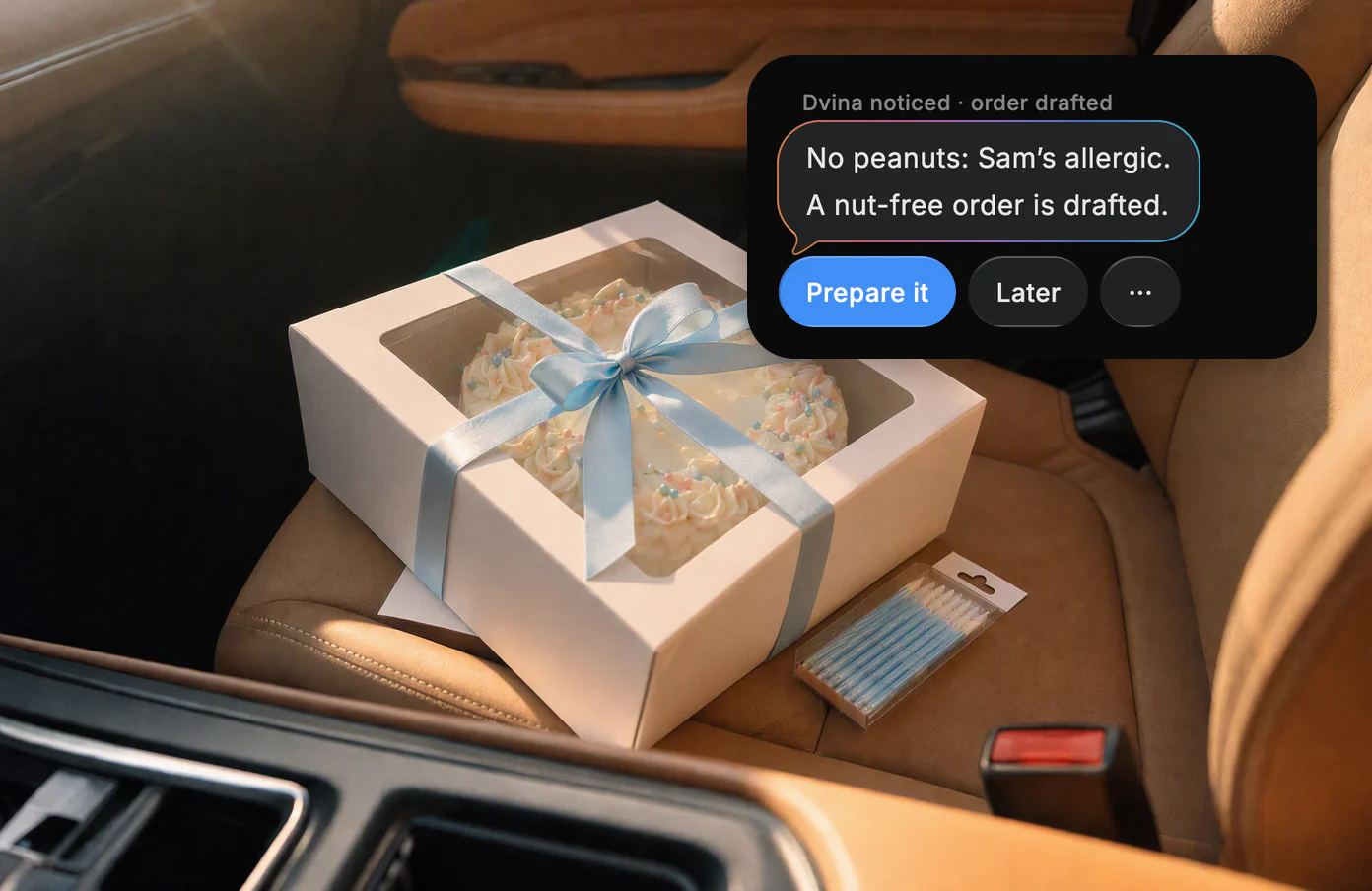 A bakery cake box tied with a blue ribbon on a car seat, with Dvina's card: No peanuts, Sam's allergic.