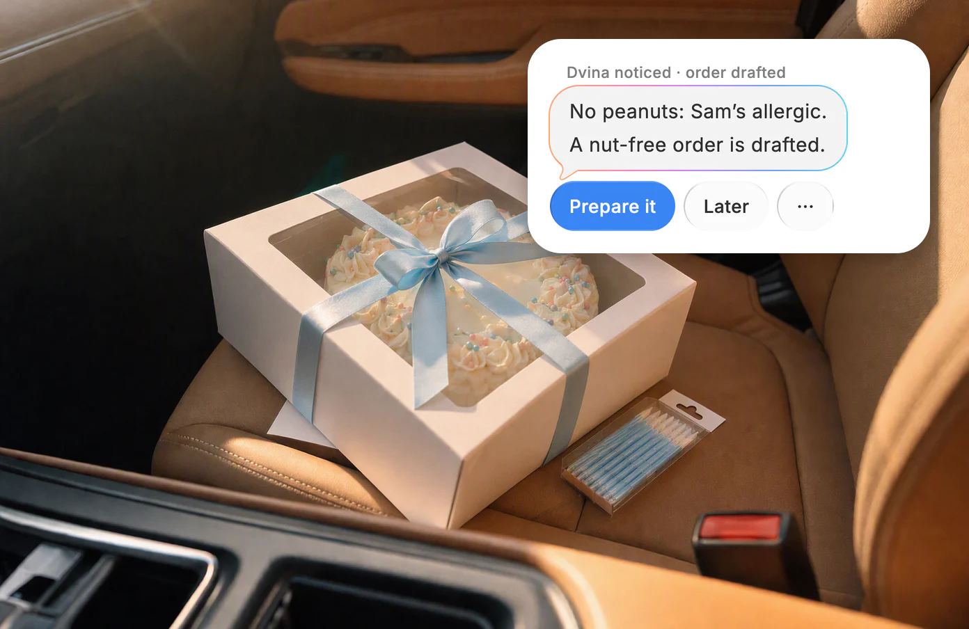 A bakery cake box tied with a blue ribbon on a car seat, with Dvina's card: No peanuts, Sam's allergic.
