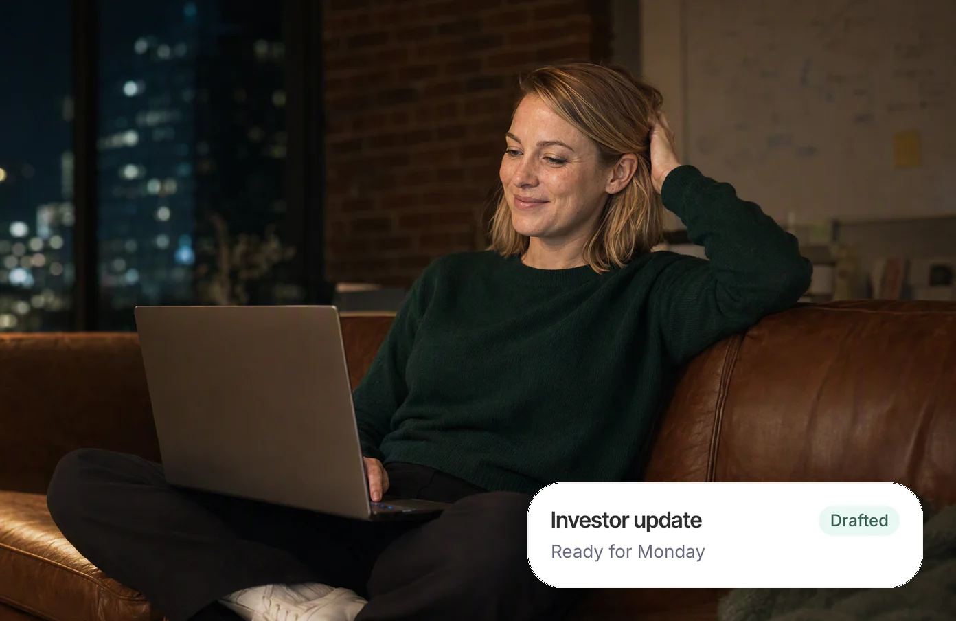 A founder cross-legged on her office sofa on a Sunday night, her laptop on her knees, grinning; her Dvina card: the investor update, drafted and ready for Monday.